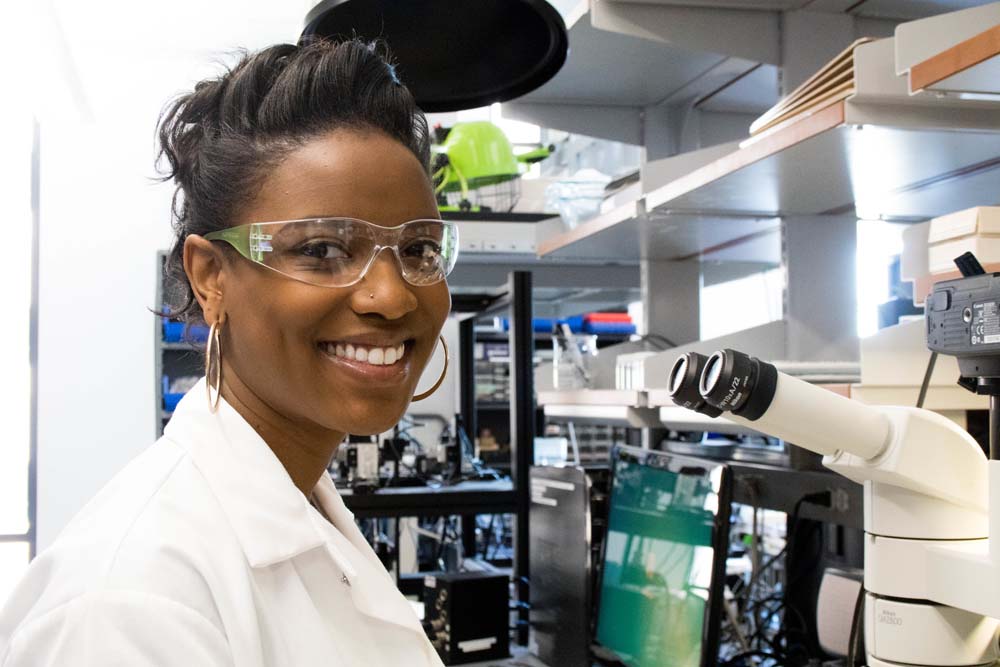 BME Engineer smiling in front of microscope 