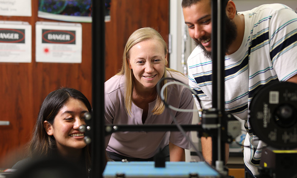 Texas BME alumna Kristen Maitland looking at lab equipment with students