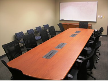 An empty conference room in BME 1.112 with chairs at a table and lining the wall