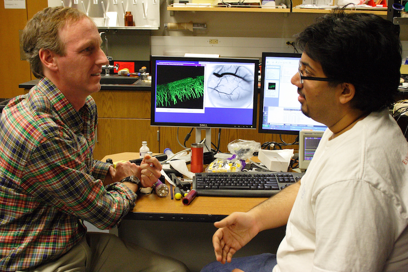 UT Austin Biomedical Engineering Professor Andy Dunn sits with a student in front of a computer