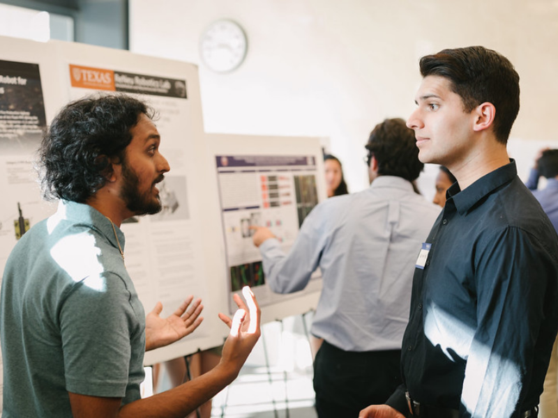 Two BME grad students talking in front of a research poster