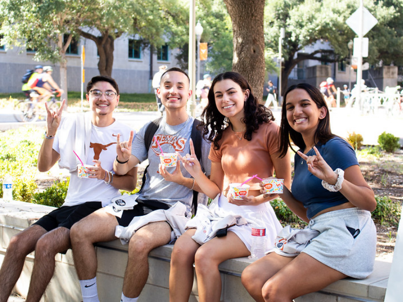 Texas BME students smiling and doing hook 'em horns hand signs while eating ice cream