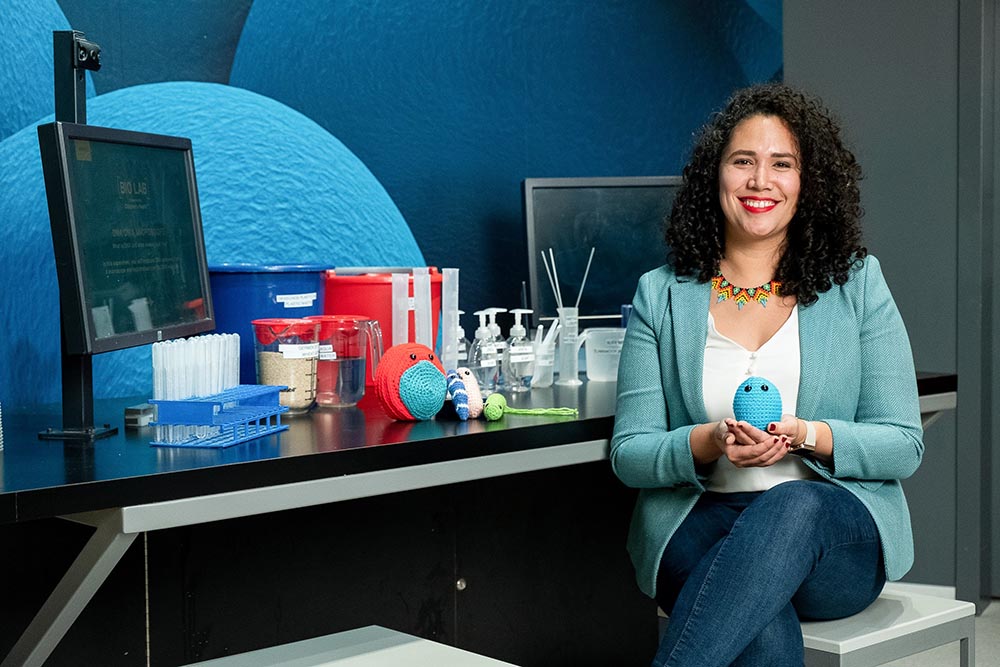 Ana Maria Porras smiling and holding a crocheted doll