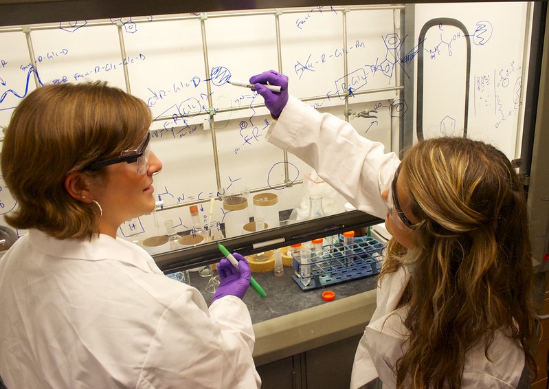 Two Texas Engineering students in lab coats working in a lab