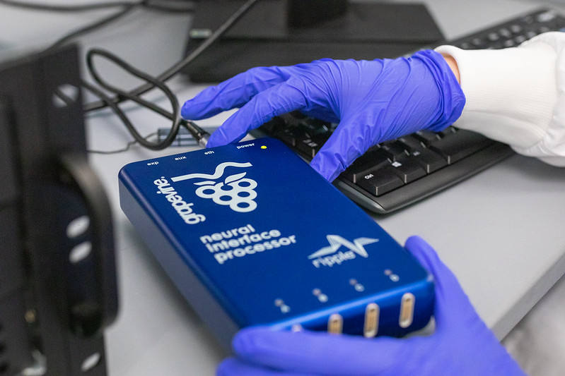 gloved hands grasping neural interface processor box