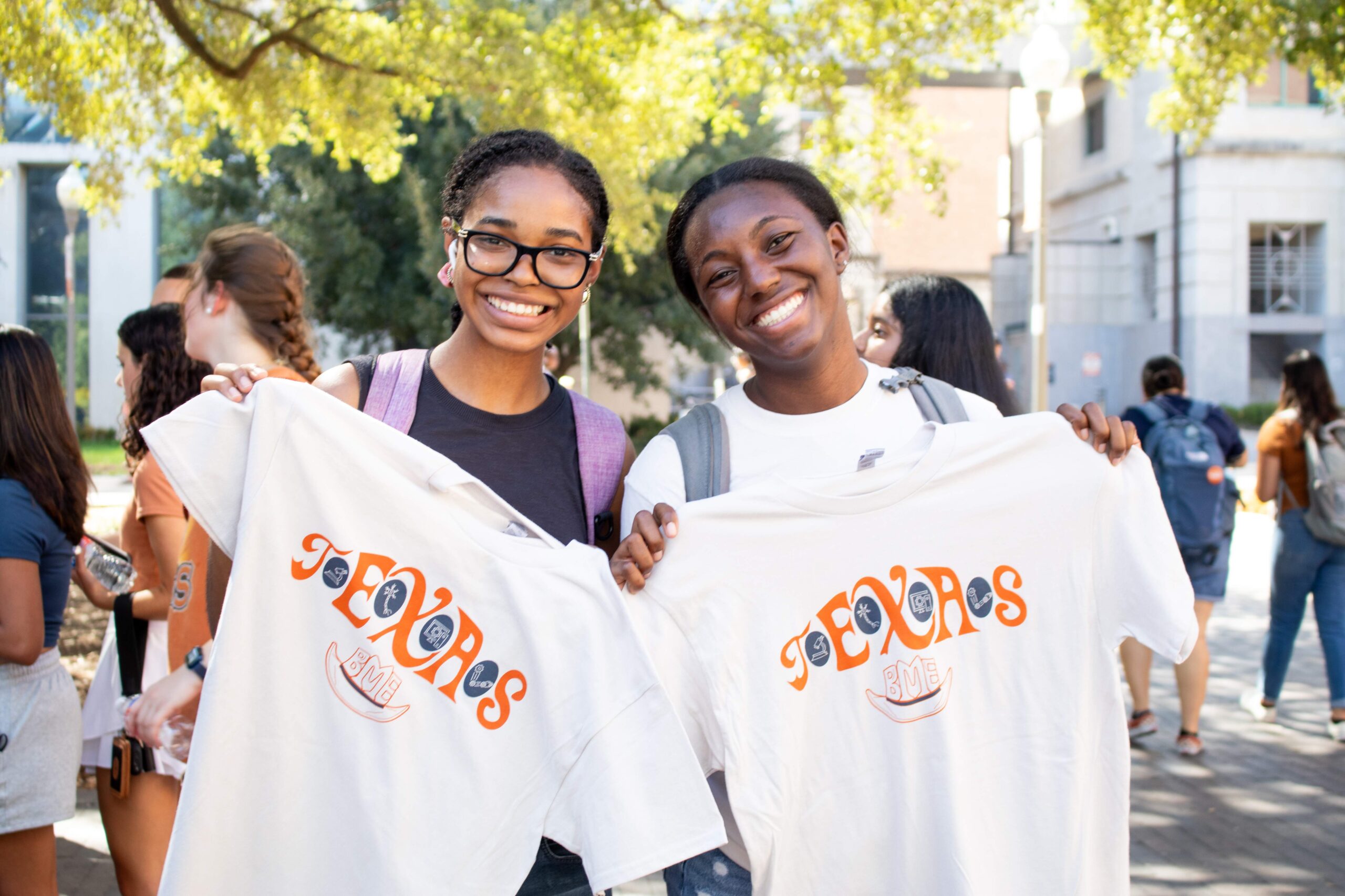 Two smiling students holding Texas t-shirts at UT Austin