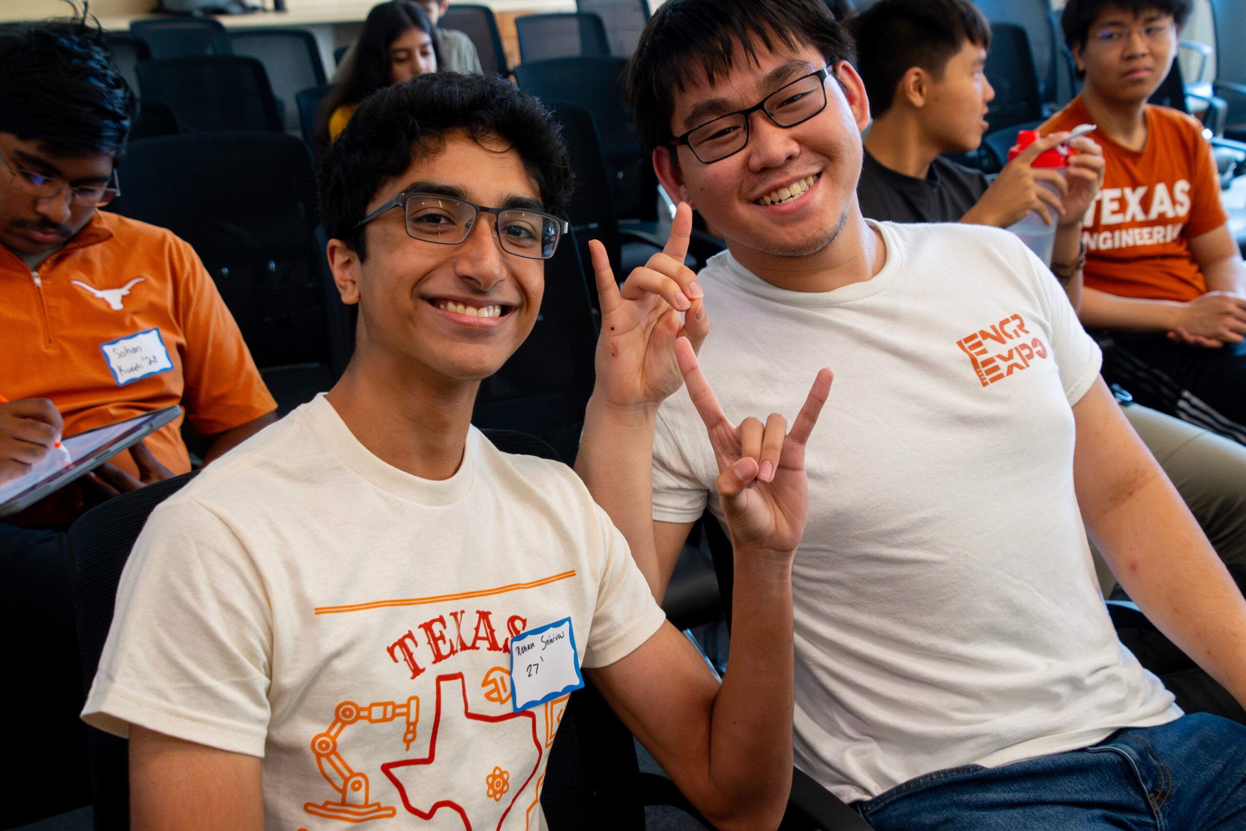Texas Engineering students doing hook 'em horns hand sign and smiling in bleachers