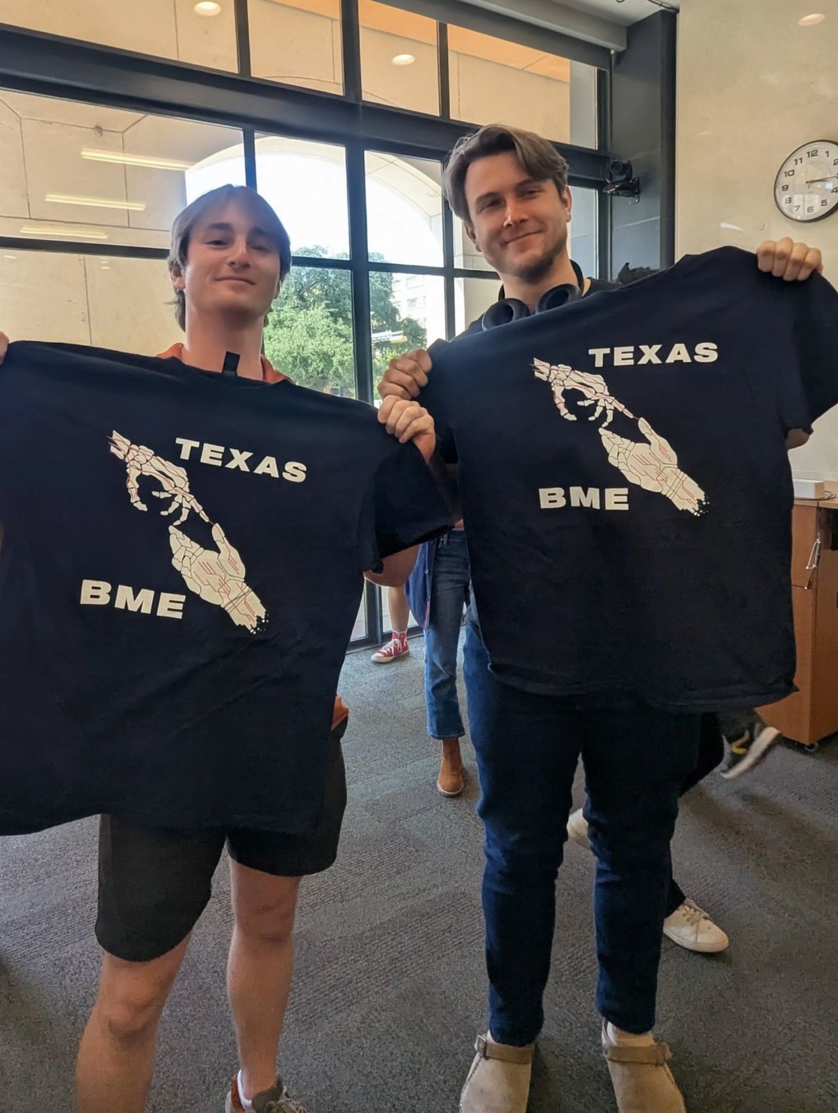 Texas BME students smiling and holding up BME t-shirts at Fall Gathering event