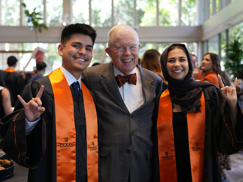 Texas Engineer Ken Diller smiling with students wearing graduation regalia