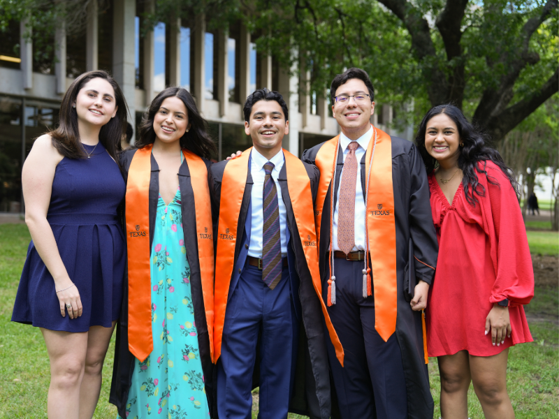 Texas Engineering students smiling in a group wearing caps and gowns