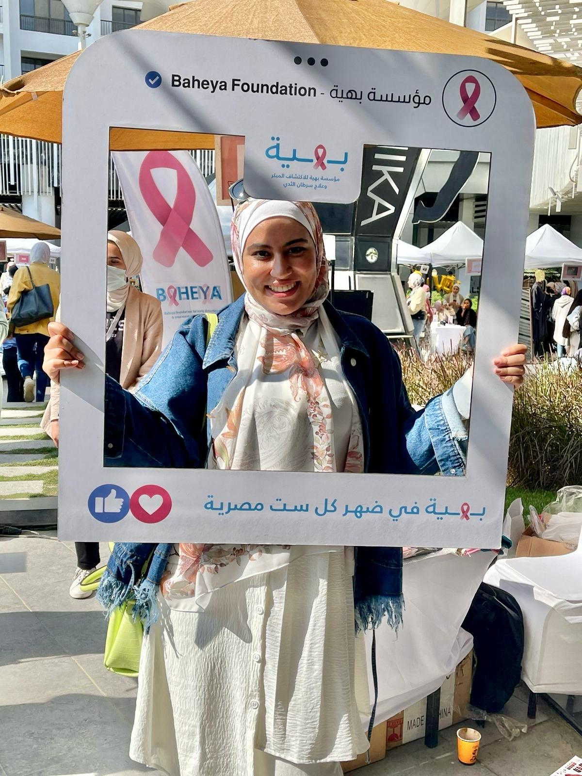 Texas BME student Alaa Melek smiling with sign board for Baheya Foundation